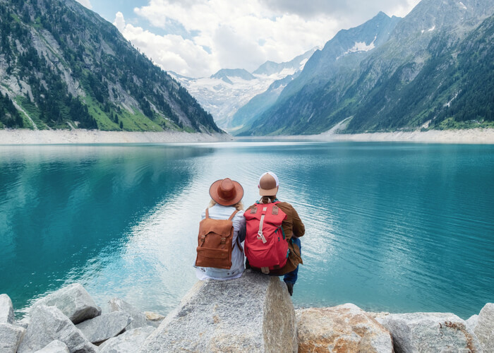 two people sitting on a rock looking out over a lake.